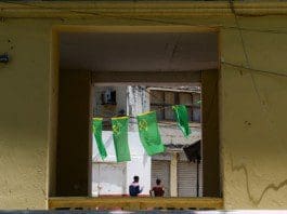 Two men walk under the flags of Tanzania's ruling party Chama Cha Mapinduzi in Stone Town of Zanzibar, Tanzania, on Oct. 28, 2015. Tanzania's semi-autonomous archipelago Zanzibar on Wednesday has cancelled results of its just-held general elections, according to Zanzibar Electoral Commission. (Xinhua/Zhai Jianlan)