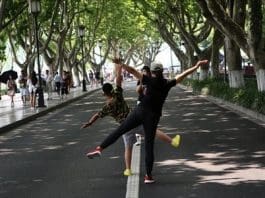 Two tourists in Hangzhou, East China's Zhejiang Province - which will host the G20 summit in September - pose for a photo on the empty street around West Lake on Thursday. As the summit approaches, traffic control measures have reduced the number of cars running on several streets around the lake. Photo: IC
