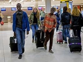 Thomas Nellon, left, 17, and his brother Johnson Nellon, 14, of Liberia, smile at their mother in the arrivals area at John F. Kennedy International Airport in New York earlier this month. The brothers received a health screening upon arrival. The U.S. says it will step up screening measures for arrivals from Ebola-affected West African countries.