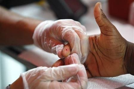 A medical technician draws a blood sample to screen for glucose and cholesterol at the National Urban League's Economic Empowerment Tour in Dallas health