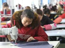 Left-behind women and poor migrant workers make down jackets ordered by customers at a poverty alleviation workshop in an industrial concentration area in Guangshan County, central China’s Henan province, March 9, 2018. (Photo from CFP)