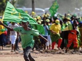 A boy runs with a flag during a ruling Chama Cha Mapinduzi (CCM) rally in Dar es Salaam, Tanzania, on October 21, 2015. CCM's party's candidate John Magufuli hopes to succeed President Jakaya Kikwete in what is seen as the tightest electoral race in Tanzania's history, as the main opposition parties unite around ex-prime minister Edward Lowassa, 61, who recently defected from the CCM. AFP PHOTO / DANIEL HAYDUK (Photo credit should read Daniel Hayduk/AFP/Getty Images)