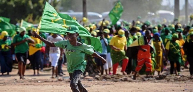TANZANIA-POLITICS-ELECTIONS A boy runs with a flag during a ruling Chama Cha Mapinduzi (CCM) rally in Dar es Salaam, Tanzania, on October 21, 2015. CCM's party's candidate John Magufuli hopes to succeed President Jakaya Kikwete in what is seen as the tightest electoral race in Tanzania's history, as the main opposition parties unite around ex-prime minister Edward Lowassa, 61, who recently defected from the CCM. AFP PHOTO / DANIEL HAYDUK (Photo credit should read Daniel Hayduk/AFP/Getty Images)