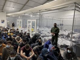 Migrants held in CBP detention with guards overlooking