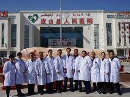 Twelve medical workers sent by east China's Anhui province to assist the People's Hospital of Pishan County in Pishan county, Hotan prefecture of northwest China's Xinjiang Uygur autonomous region, pose for a group photo in front of the People's Hospital of Pishan County, March 4, 2021. (Photo/Official website of the Health Commission of Anhui Province)