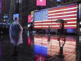 People are seen in the rain caused by tropical storm Henri, in Times Square in New York, the United States, on Aug. 22, 2021. (Xinhua/Wang Ying)