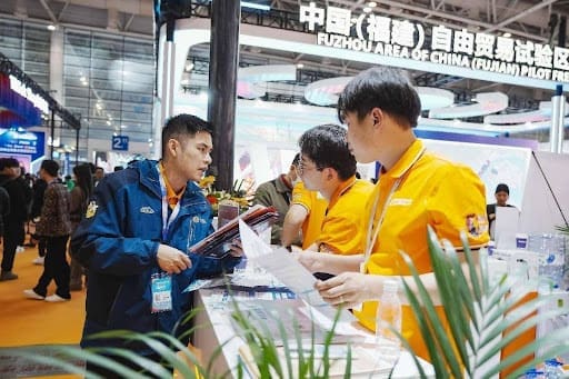 Staff members of an exhibitor at the 4th China Cross-border E-commerce Trade Fair in Fuzhou, southeast China's Fujian province talk to a visitor, March 18, 2024. (Photo by Xie Guiming/People's Daily Online) Staff Members Of An Exhibitor At The Th China Cross Border E Commerce Trade