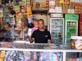 Retailer With Smartphone And Wide Shop View
