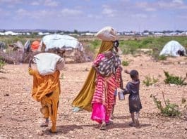 A Somali mother and her children displaced by flooding search for a place to take shelter among other families who have already found refuge on higher ground. Photo credit: IOM/ Ismail Abdihakim Ismail