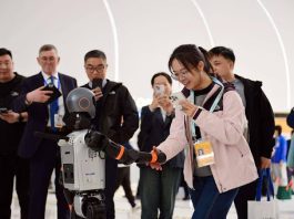 A journalist shakes hands with a robot at the 2025 Zhongguancun (ZGC) Forum Annual Conference in Beijing. (Photo by Chen Bin/People's Daily)