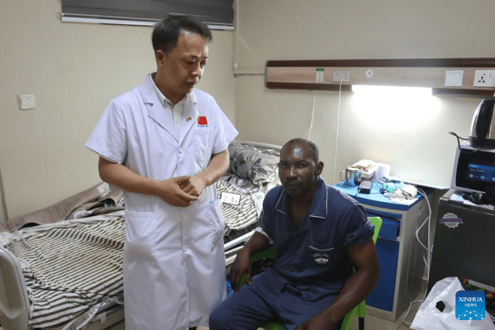 Yang Yongguang (L), chief of the 14th Chinese medical team to Ghana, visits patient Godwin Segrah after his surgery in Accra, Ghana, July 25, 2025. The 14th Chinese medical team and Ghanaian doctors have successfully carried out the first laparoscopic transabdominal anterior hernia repair within the West African country's public hospital system on Wednesday. (Xinhua/Gao Jianfei)