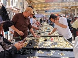 Tourists buy raw jade in a market in Hotan, northwest China's Xinjiang Uygur autonomous region. (Photo by Xu Xiaolong)